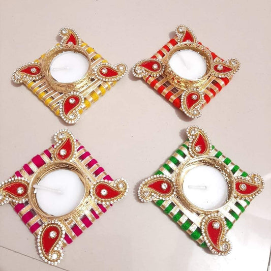 Four decorative square candle holders arranged in a 2x2 grid on a light beige background. Each holder has a gold-tone frame with red enamel details and white pearl-like embellishments, with striped bands in yellow, red, pink, and green.