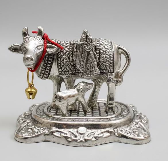 Decorative silver figurine of a cow with a calf and a person on a gray background